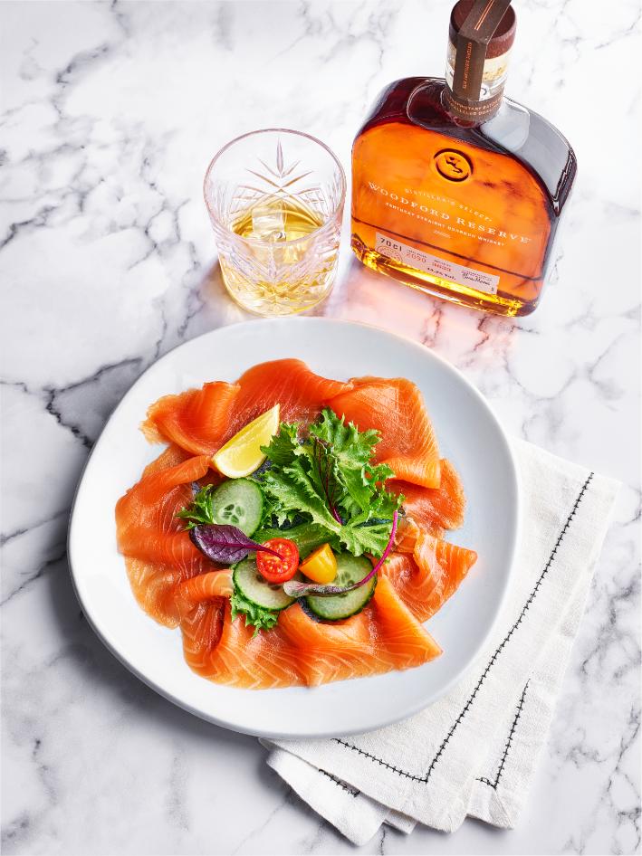 smoked salmon on a plate, with a glass of Woodford Reserve in the background